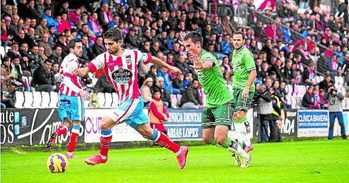 El capitán del Lugo conduce el balón ante la mirada de un futbolista del Racing. El capitán del Lugo conduce el balón ante la mirada de un futbolista del Racing.